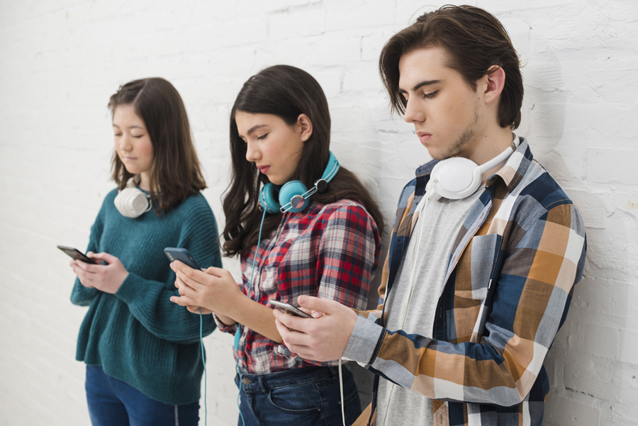 Tres jóvenes mirando sus celulares